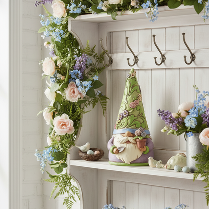 A styled white wooden shelf display decorated with a lush floral garland, a small decorative gnome figure, metal hooks, and multiple bouquets in pink, lavender, and blue flowers.