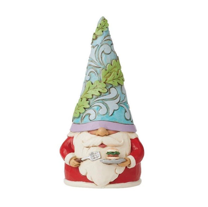 A decorative garden gnome figurine wearing a tall pointed hat with green leaf patterns on a light blue background, a red coat, and a white beard, holding a small plate.