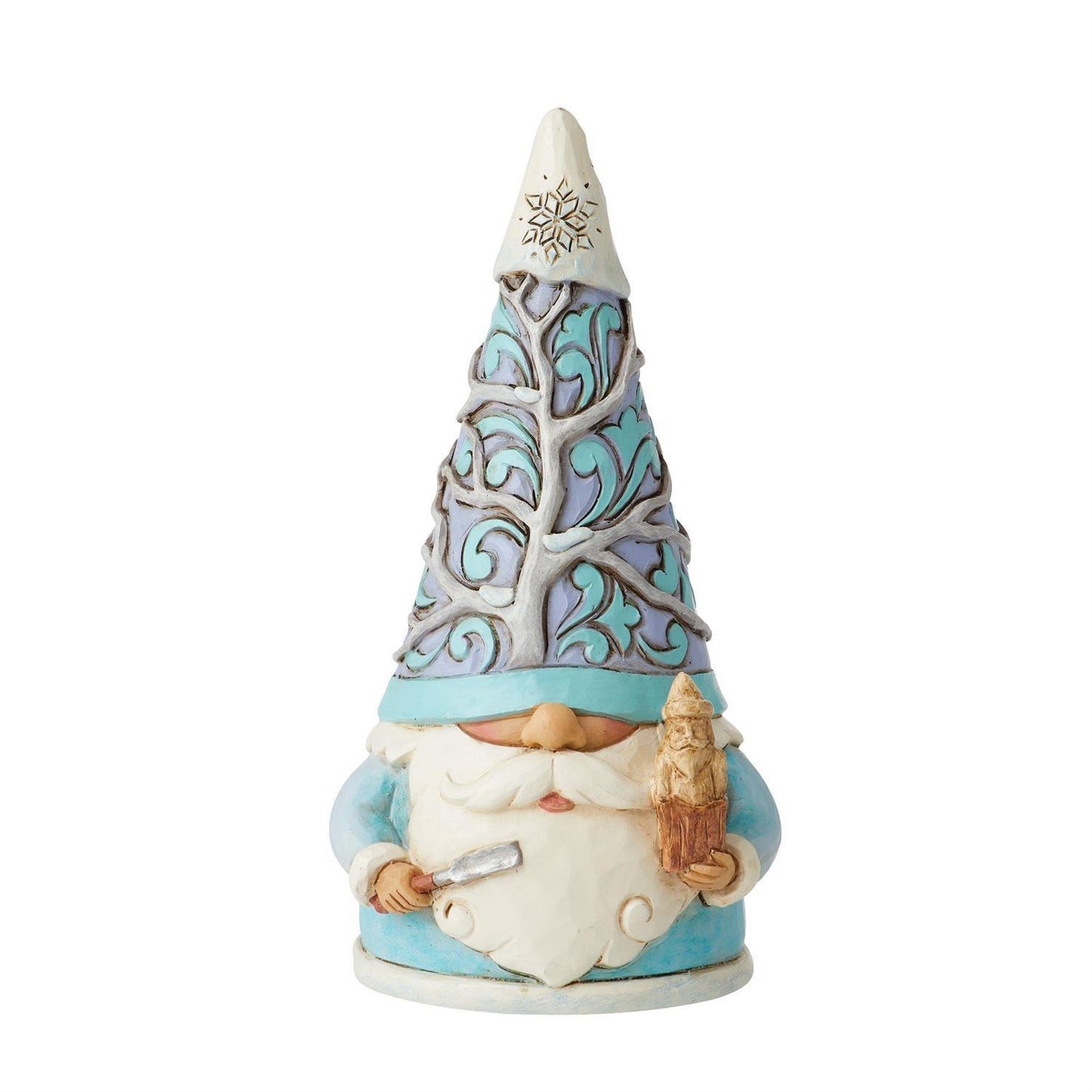 A decorative gnome figurine with a tall pointed hat decorated with blue and lavender scrollwork and a white snowflake at the tip. The gnome has a white beard, a light blue outfit, and holds a small brown tree in one hand and a silver tool in the other, set against a plain white background.