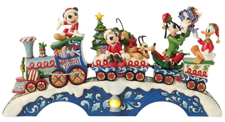 A Disney-themed Christmas decorative figurine featuring Mickey Mouse, Minnie Mouse, Goofy, Donald Duck, and Pluto riding a decorated train on a snowy base.