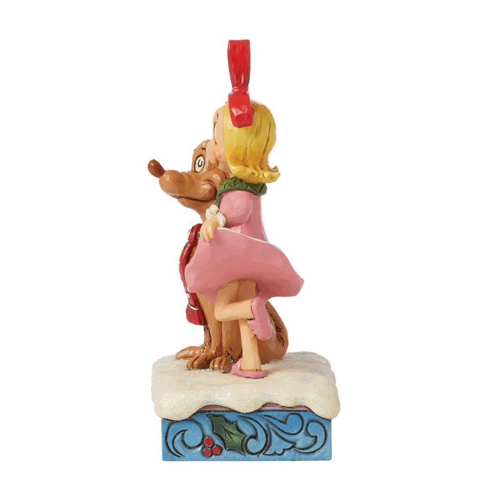A decorative figurine of a woman in a pink dress and red bow embracing a brown dog on a snowy base with a blue patterned bottom, shown on a plain white background.