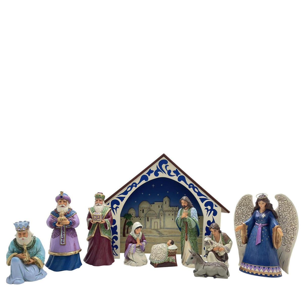 A nativity scene figurine set on a plain white background, featuring an angel, three wise men, a baby in a manger, a kneeling figure, and a small stable with a blue and white patterned backdrop.