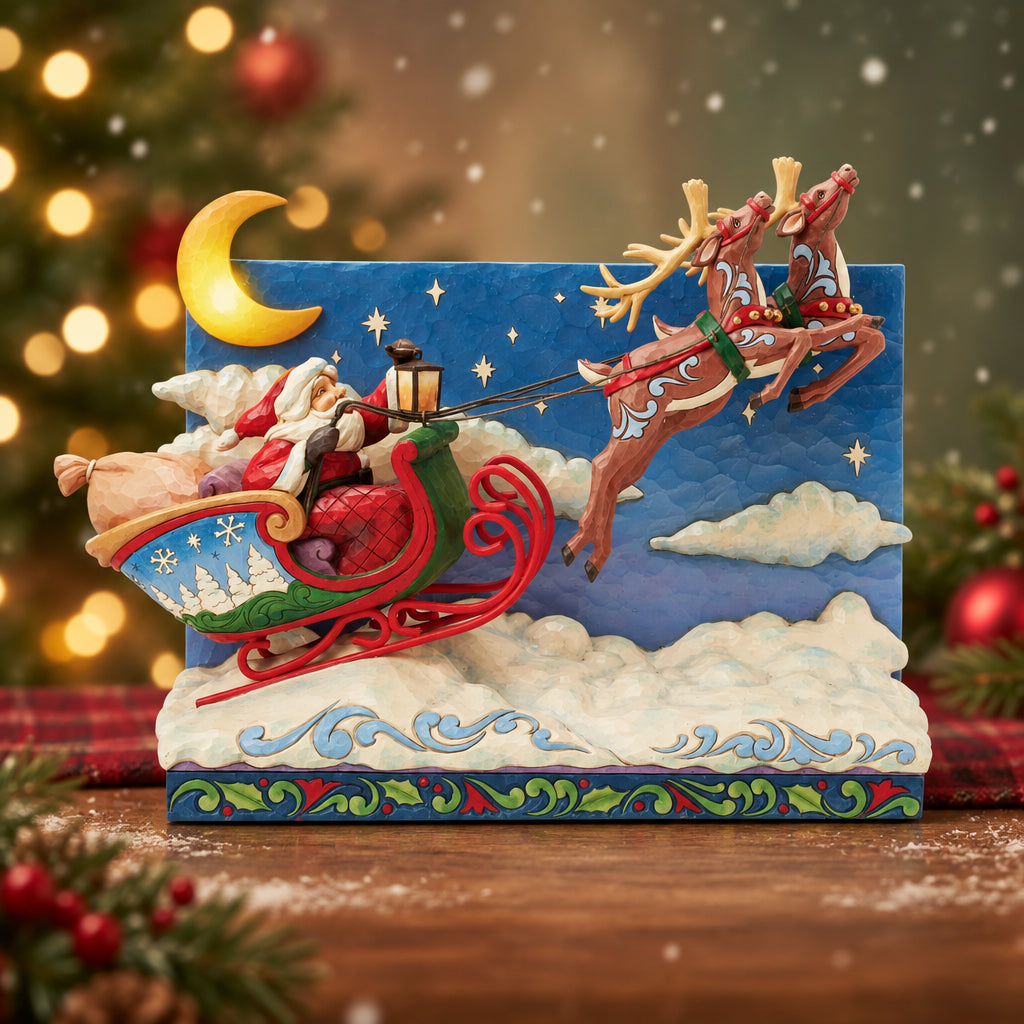 A decorative Santa Claus holiday figurine showing Santa in a red sleigh pulled by three brown reindeer against a night sky backdrop with a yellow crescent moon and clouds.