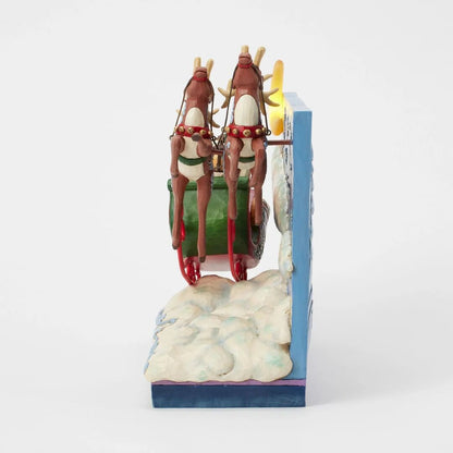 Decorative bookend with cartoonish reindeer on skis and green sled against a white background