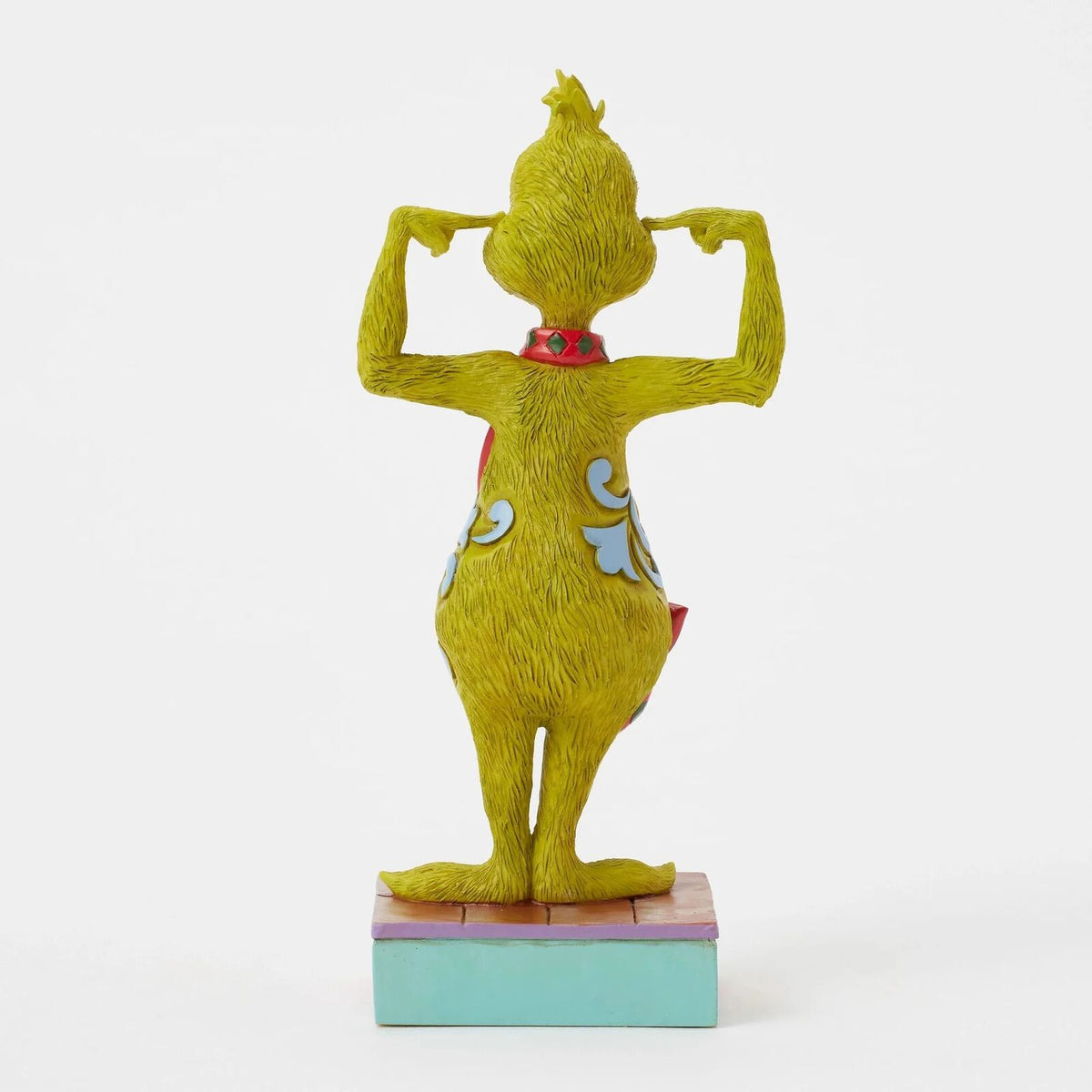 A collectible figurine of the Grinch from The Dr. Seuss World Building Exhibition, shown from the back wearing a red vest and blue patterned pants, standing on a colorful base against a white background.
