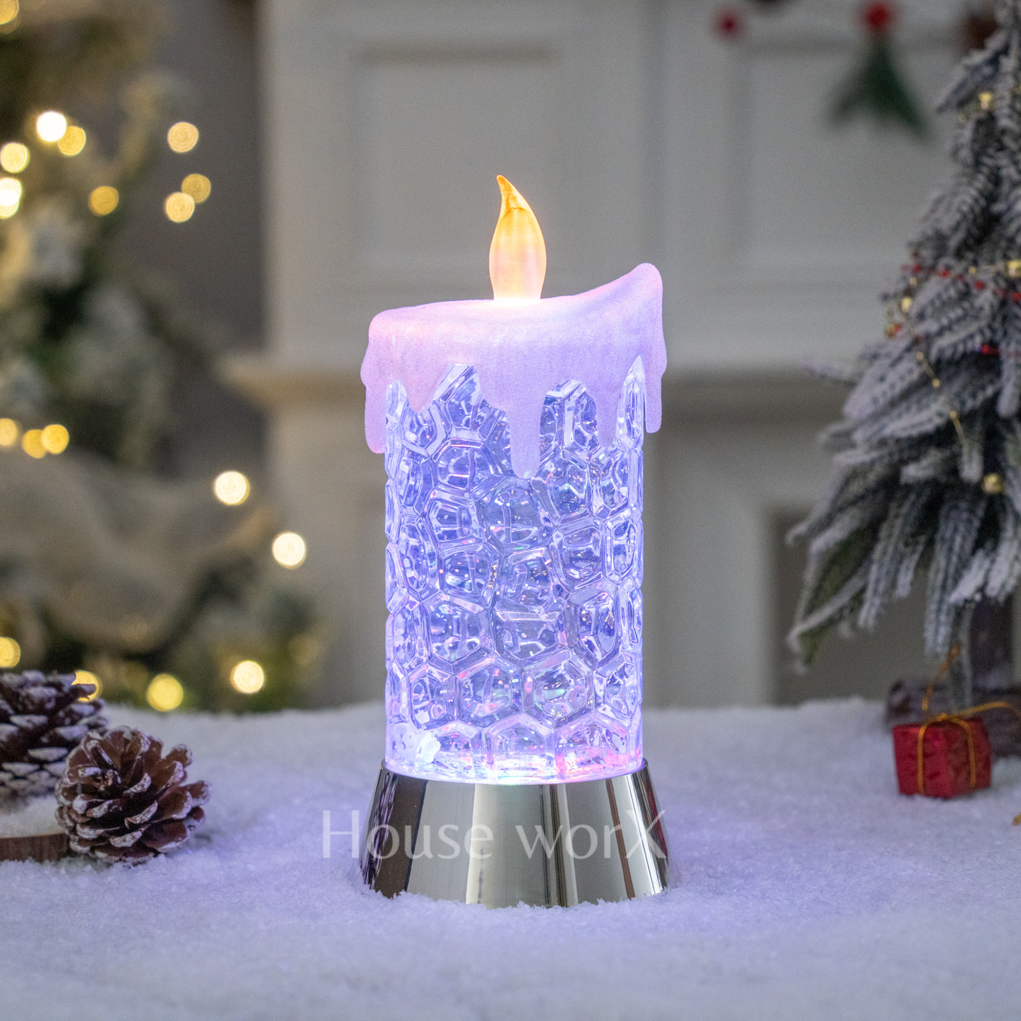 Decorative LED candle with lace design in a festive setting with Christmas trees and lights.
