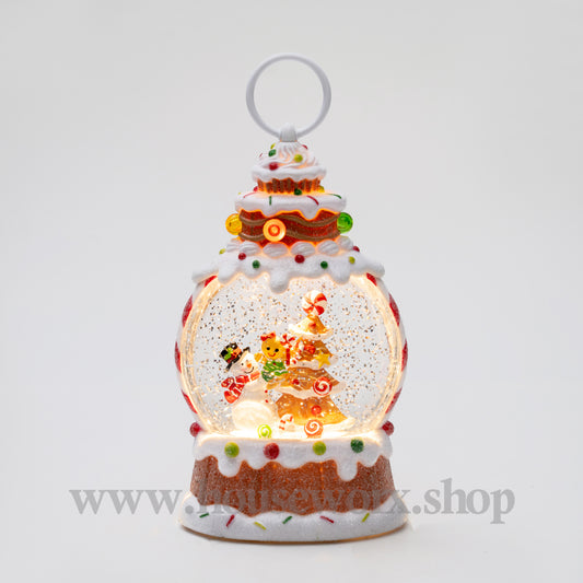 Decorative snow globe with a gingerbread house design on a white background