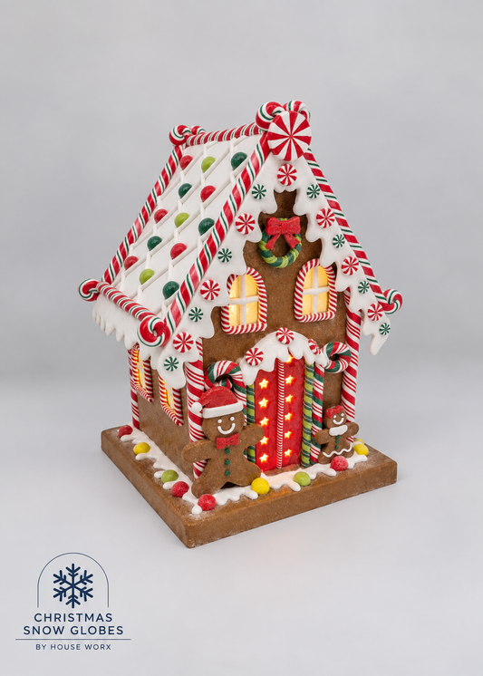 A decorated gingerbread house Christmas ornament with candy cane details, snow globes, and festive icing, displayed on a neutral light gray background with a 'Christmas Snow Globes by House Work' logo in the bottom-left corner.
