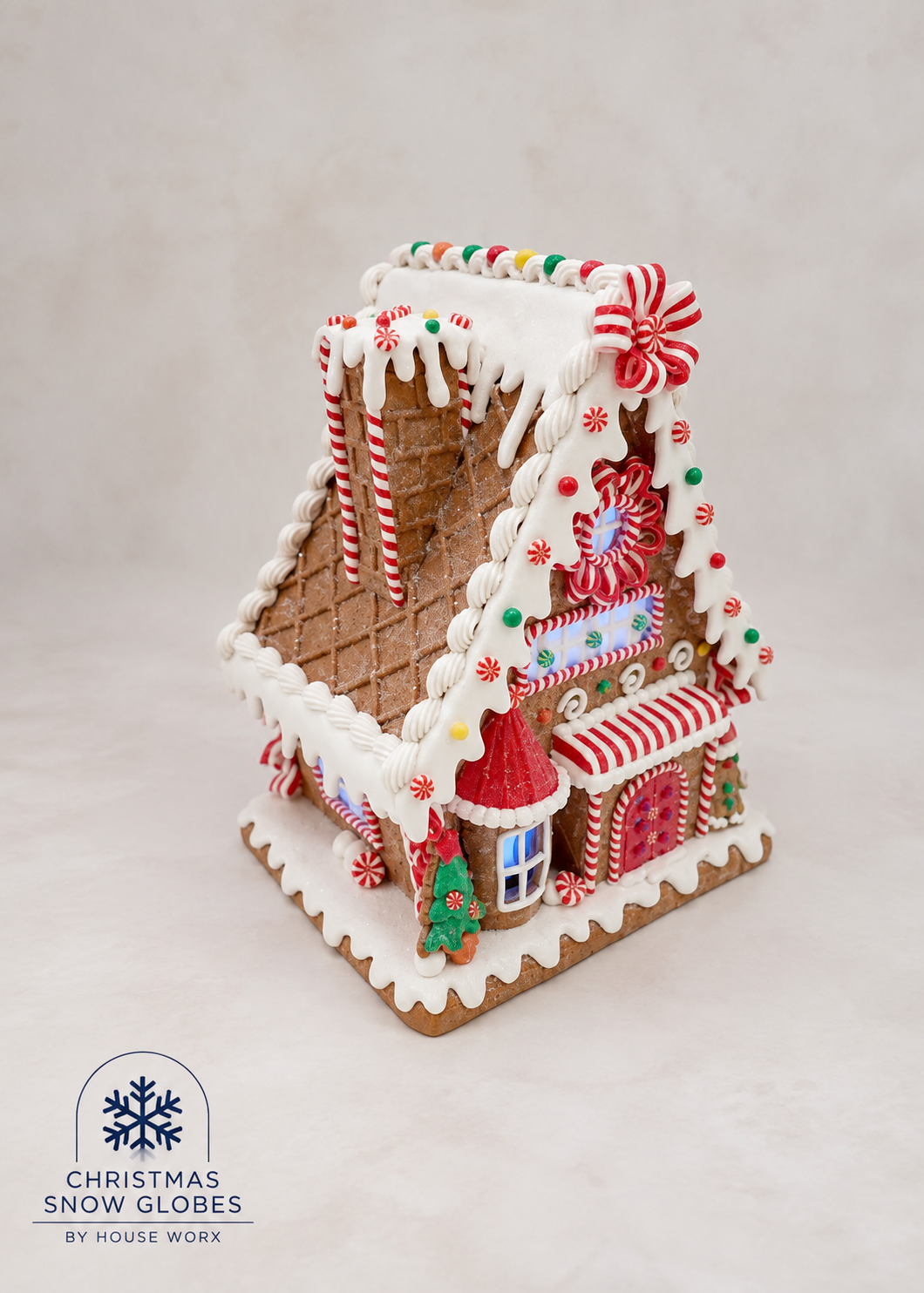 A decorated gingerbread house Christmas snow globe ornament with white icing, red and white candy cane details, and colorful sprinkles, shown on a light neutral background with a 'Christmas Snow Globes by House Work' logo in the bottom-left corner.