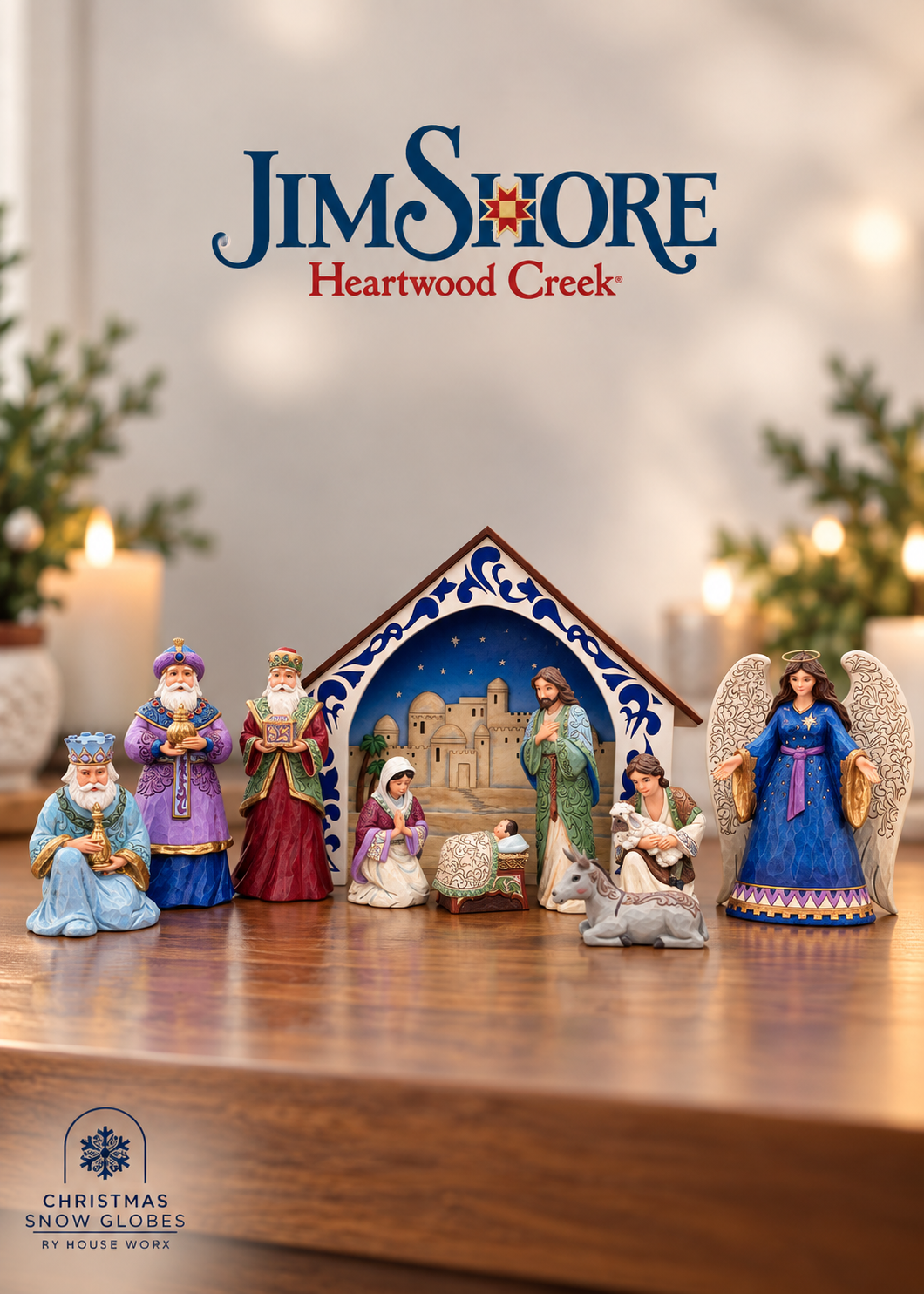 A Christmas nativity scene set displayed on a wooden table, featuring a stable, Mary, Joseph, baby Jesus, the three wise men, and an angel. The background is softly blurred with warm lights and greenery, and the Jim Shore Heartwood Creek logo is visible at the top.