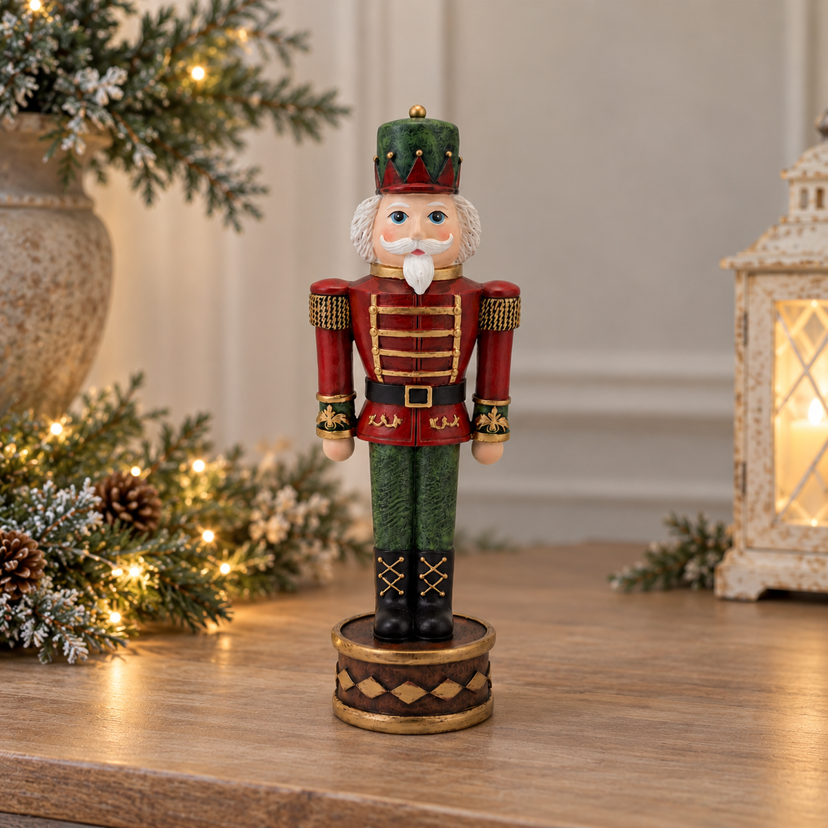 A decorative Christmas nutcracker figurine standing on a round base, placed on a wooden surface with holiday greenery and a lantern in the softly blurred background.