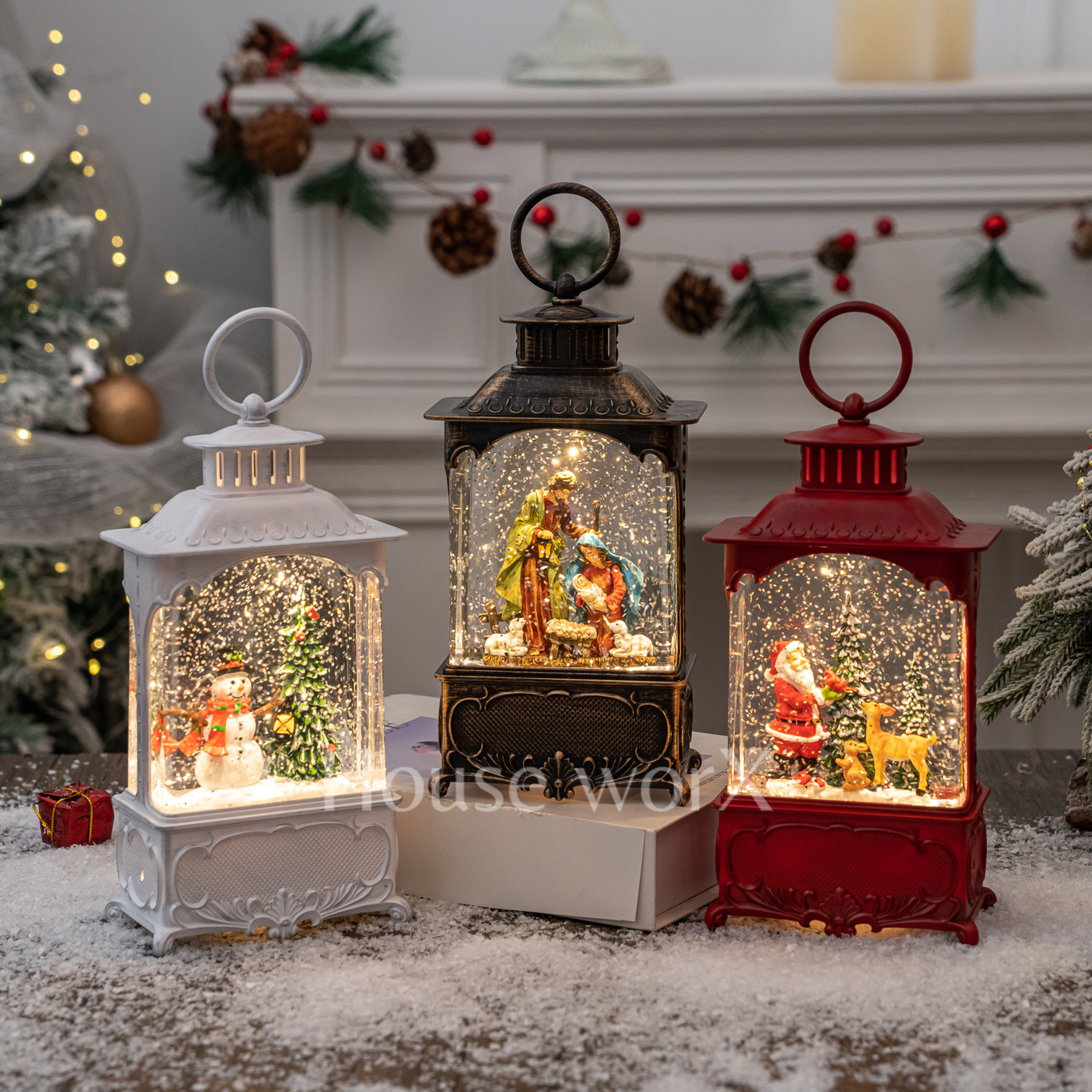 Three decorative lanterns with Christmas scenes inside, placed in front of a decorated fireplace.