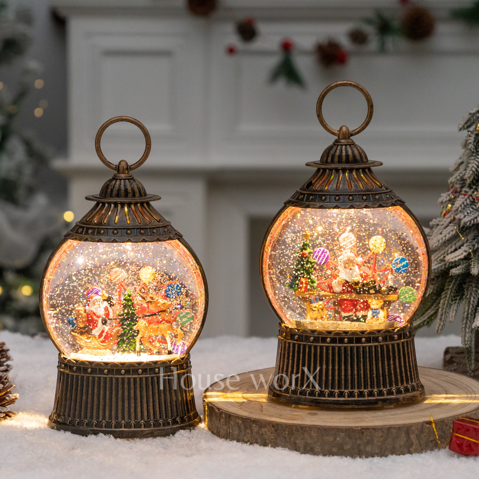 Two decorative lantern-style snow globes with Christmas scenes on a snowy surface.