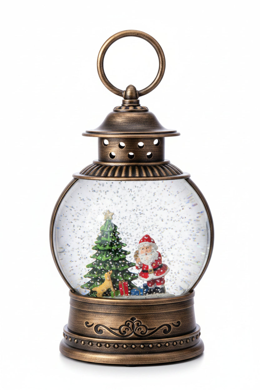 A vintage-style bronze lantern snow globe with a Santa Claus and Christmas tree scene inside, set on a dark granite countertop with a white sheet in the background.