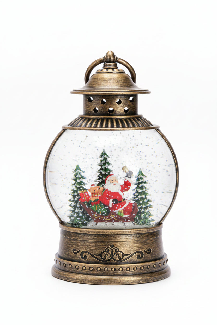 A decorative Christmas snow globe lantern with an antique bronze-colored metal base and top, featuring Santa Claus in a sleigh surrounded by pine trees inside a clear
