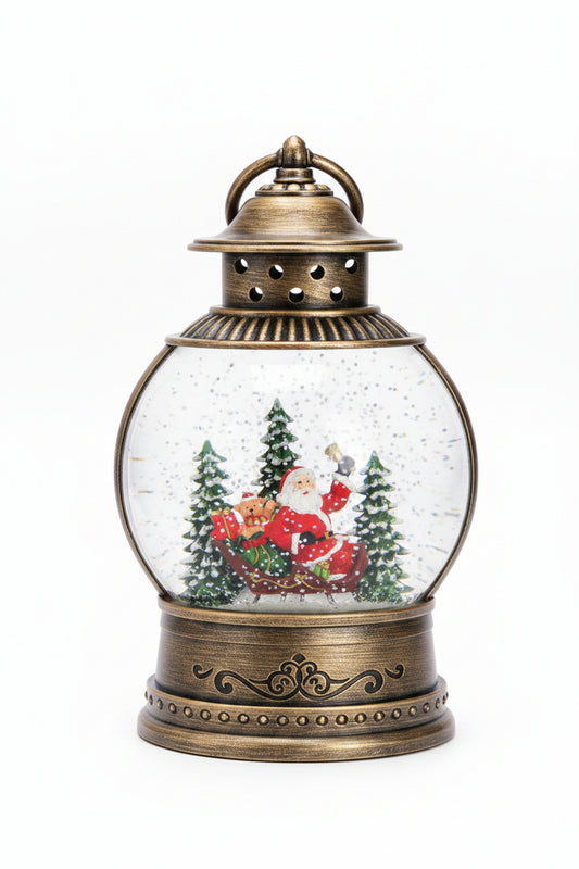 A decorative Christmas snow globe lantern with an antique bronze-colored metal base and top, featuring Santa Claus in a sleigh surrounded by pine trees inside a clear