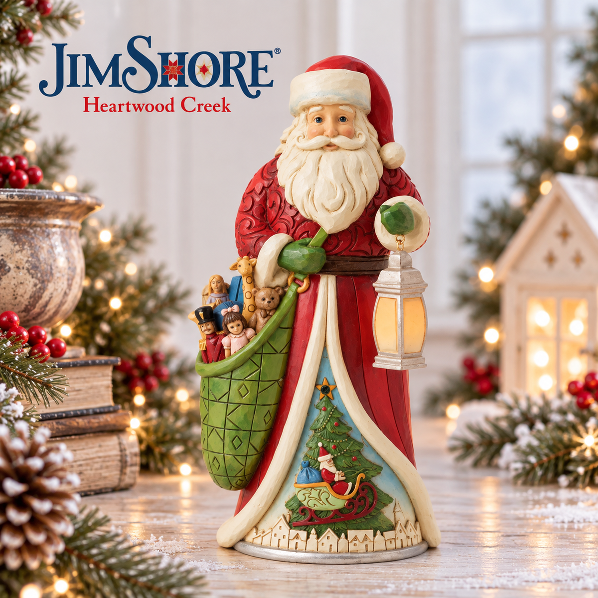 Jim Shore Heartwood Creek Santa Claus figurine holding a lantern and a green sack of toys, displayed on a decorated holiday table with lights, pinecones, and a house backdrop.