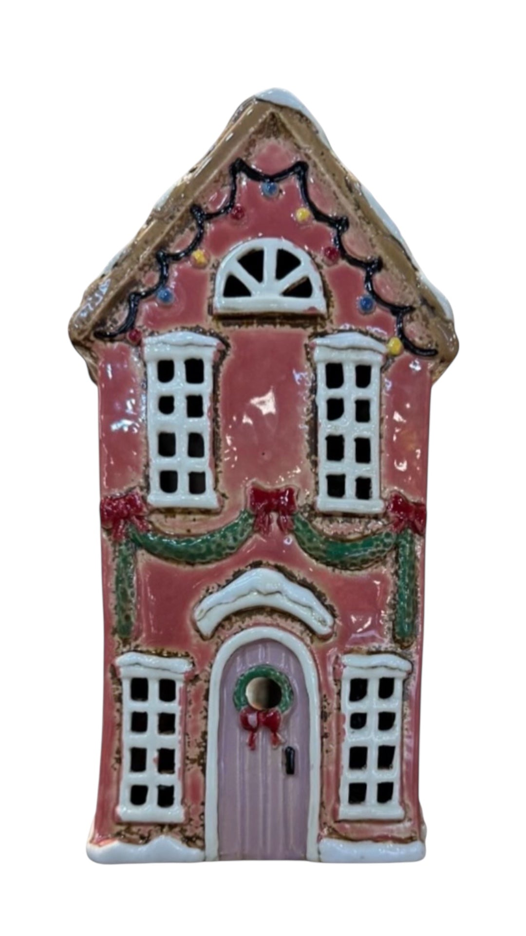 Decorative gingerbread house with pink facade and white details on a white background