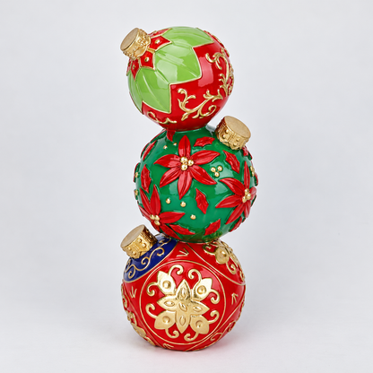 Three stacked Christmas ornaments in glossy red and green with gold decorative patterns and gold caps, photographed on a clean white background.