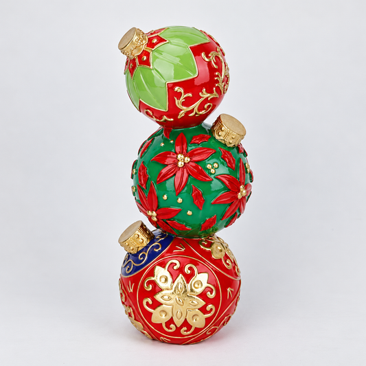 Three stacked Christmas ornaments in glossy red and green with gold decorative patterns and gold caps, photographed on a clean white background.