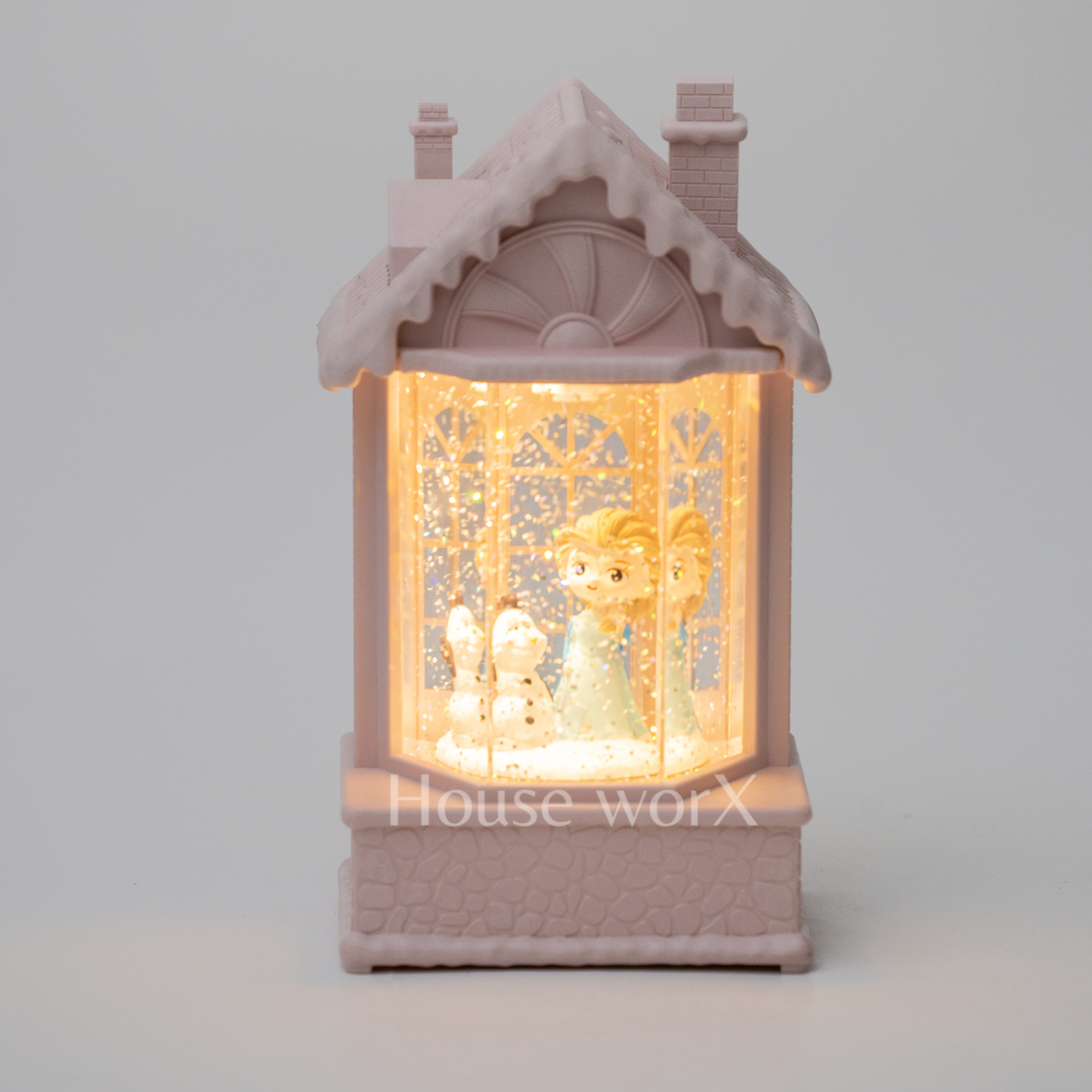Decorative lamp shaped like a house with a warm glow on a light gray snow globebackground