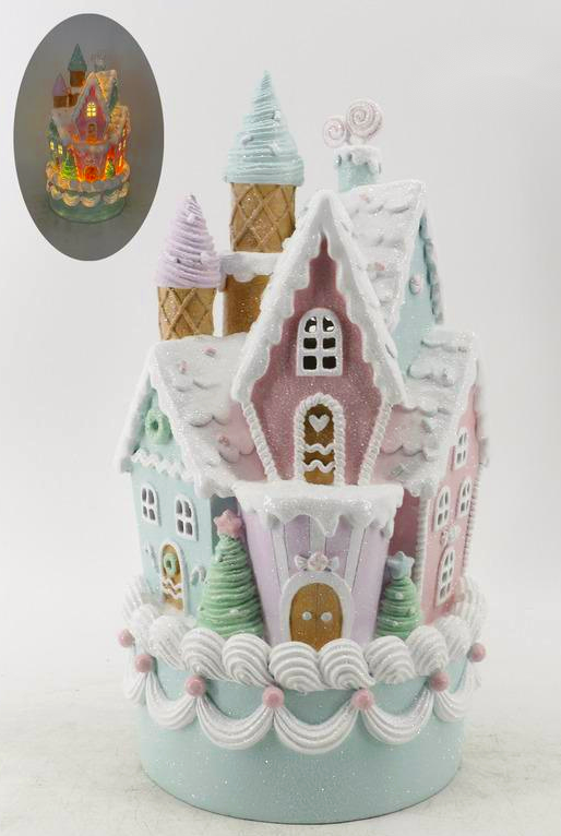 A decorative gingerbread-style castle ornament or cake topper with pastel pink, mint green, lavender, and white icing details, shown on a plain light background. A small oval inset at the upper left shows the item lit up from within.