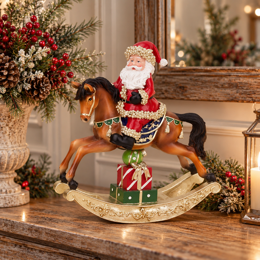 A festive Christmas-themed rocking horse figurine featuring Santa Claus riding a brown horse with gold and blue decorative details, set on a gold-colored rocking base with wrapped presents, displayed on a wooden mantel in a warmly lit holiday setting.