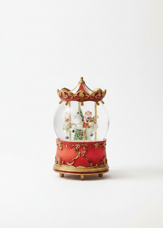 A miniature red and gold carousel music box snow globe, featuring a clear glass dome with tiny painted carousel horses inside, set against a plain white background.