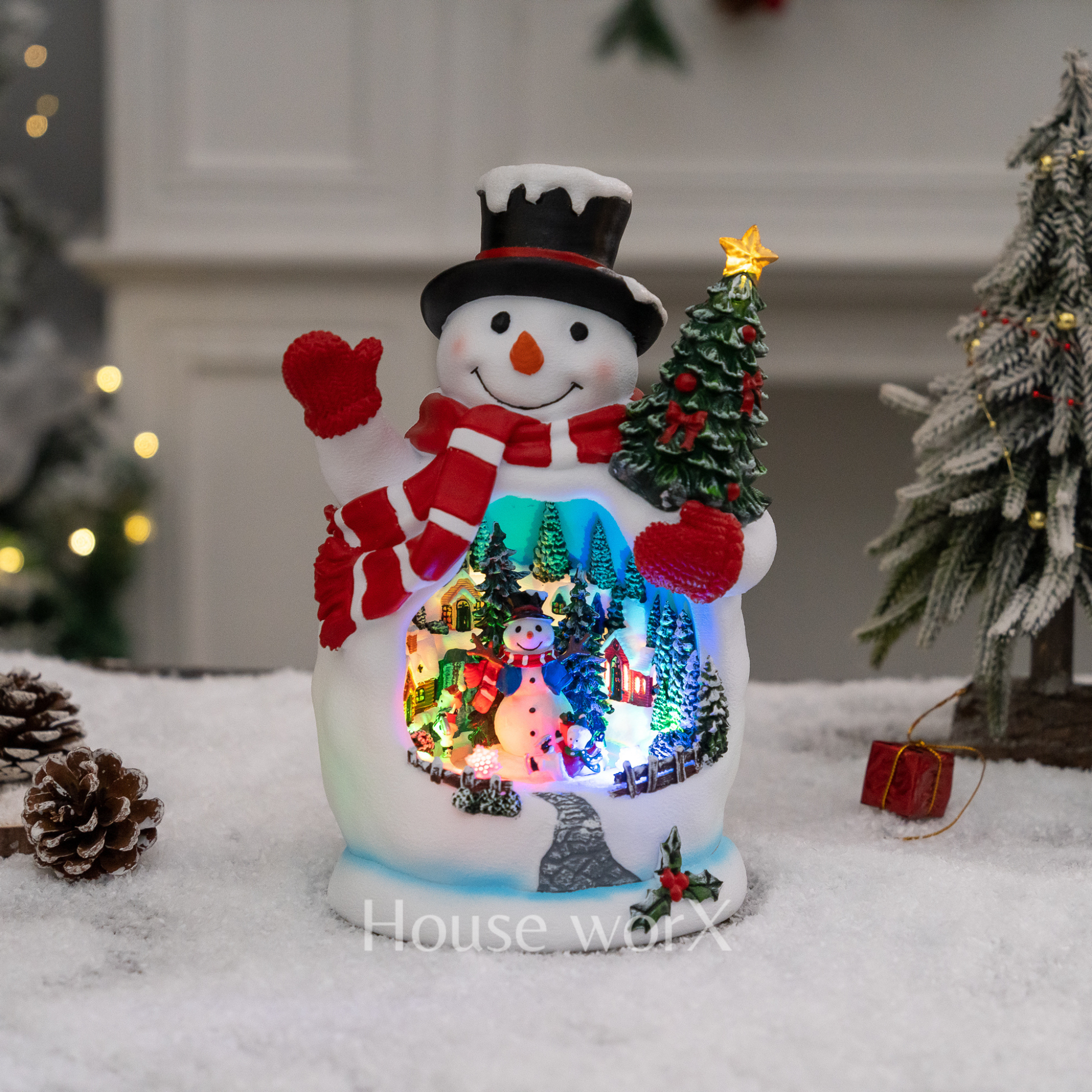 Decorative snowman with a lit-up scene inside, surrounded by Christmas trees and decorations.