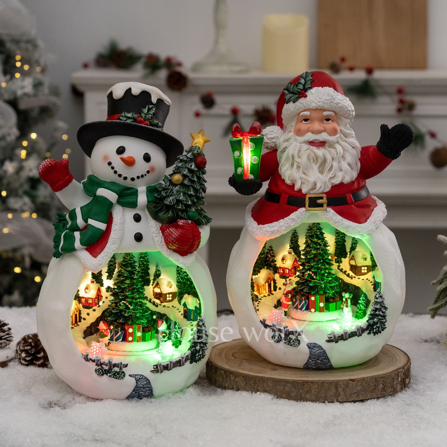 Decorative snowman and Santa Claus figures with lit scenes inside, on a snowy surface.