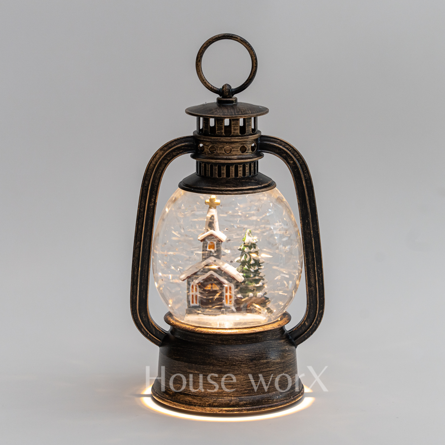 Decorative lantern with a miniature snowy scene inside on a gray background