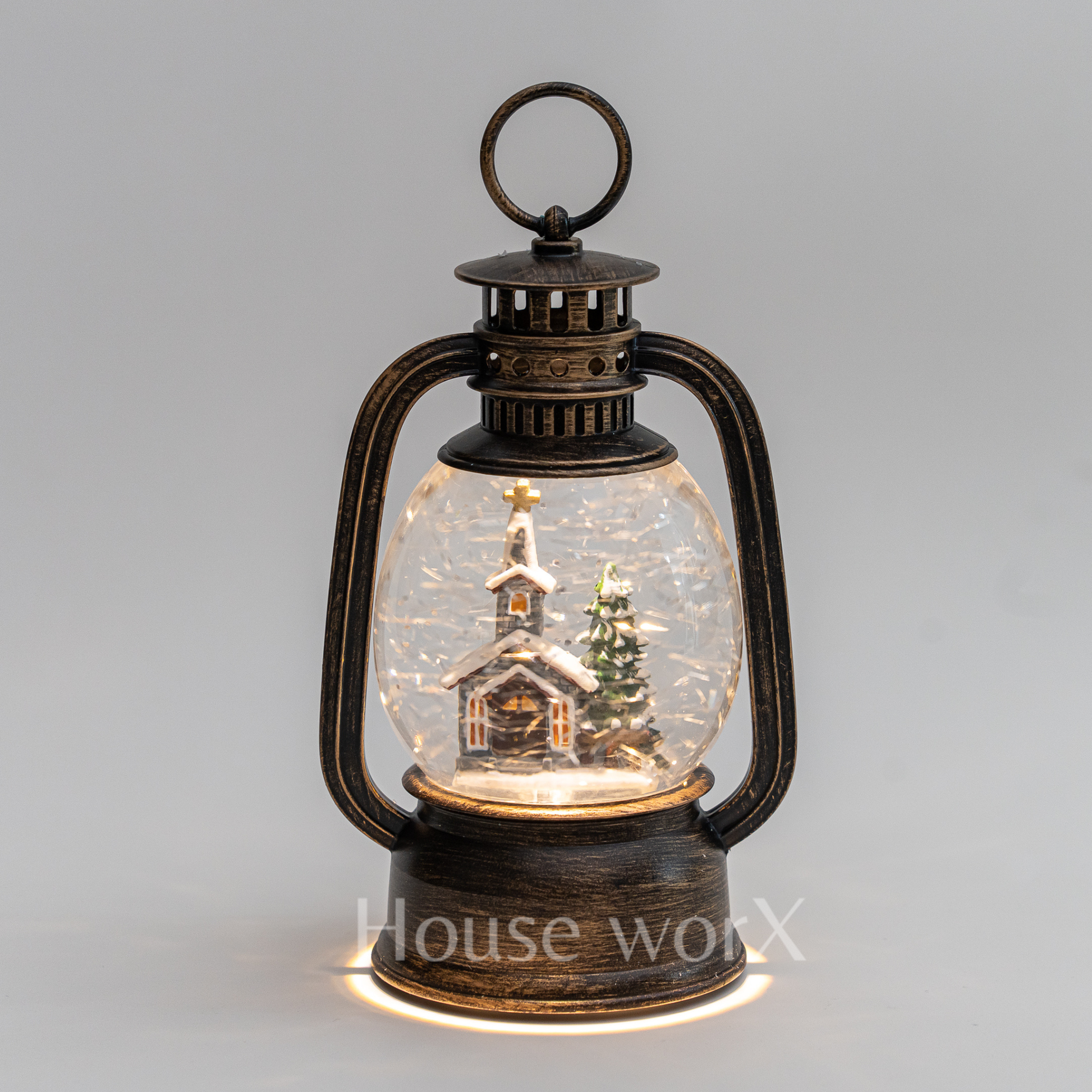 Decorative lantern with a miniature snowy scene inside on a gray background
