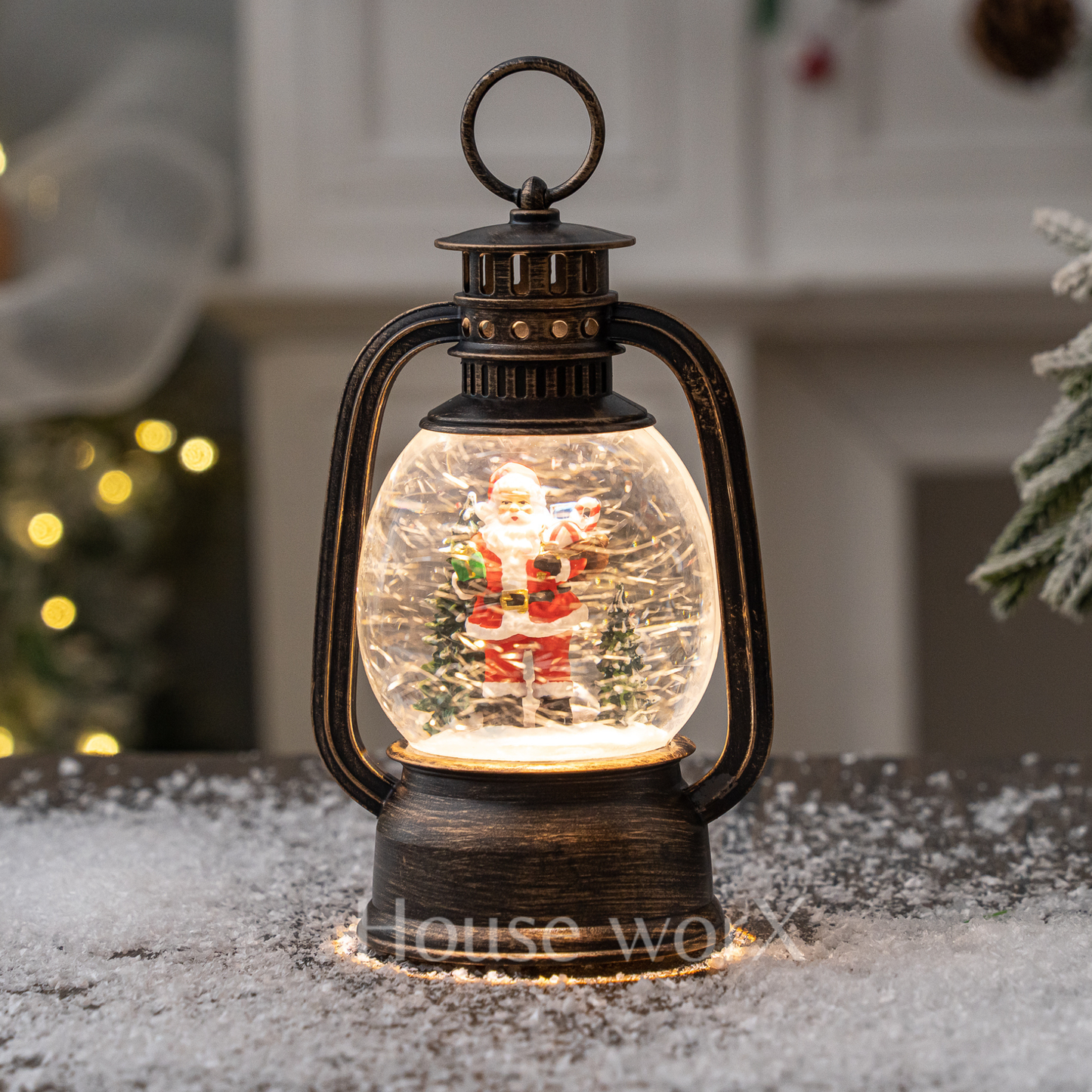 Decorative lantern with a Santa Claus snow globe inside, on a snowy surface.