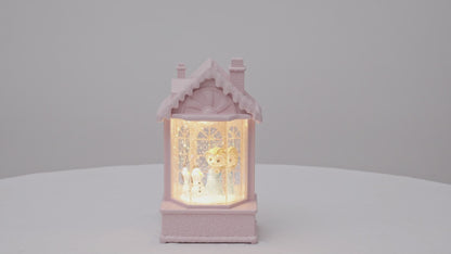 Decorative lamp shaped like a house with a warm glow on a light gray snow   video