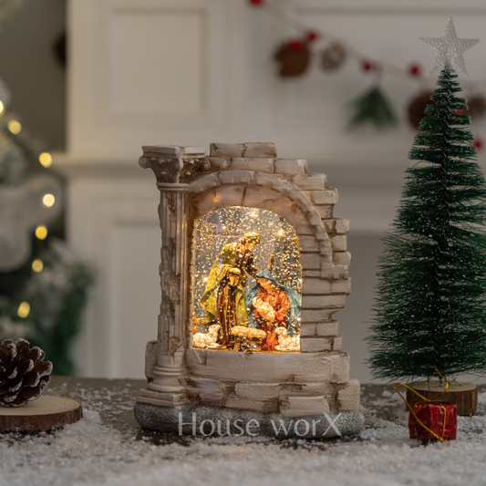 Decorative Nativity scene in a stone arch with lights, surrounded by Christmas decorations. Christmas Snow Globe