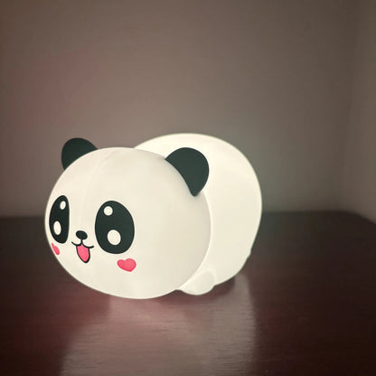 Panda-shaped night light on a dark surface with a dark background