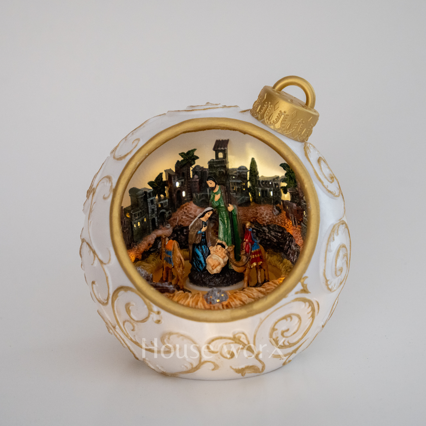 Decorative Christmas ornament with nativity scene inside a white and gold ball.