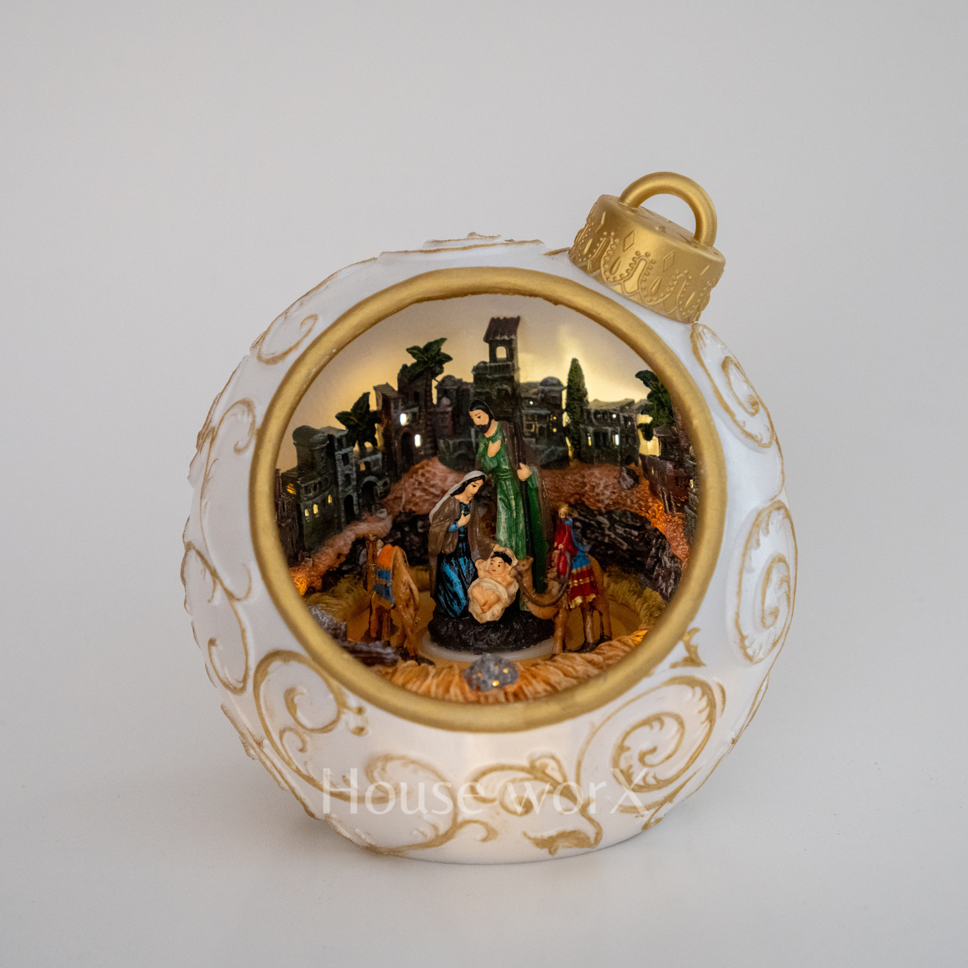 Decorative Christmas ornament with nativity scene inside a white and gold ball.