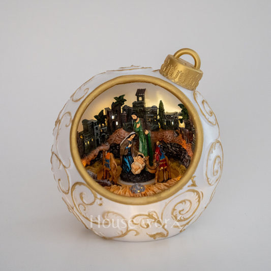 Decorative Christmas ornament with nativity scene inside a white and gold ball.