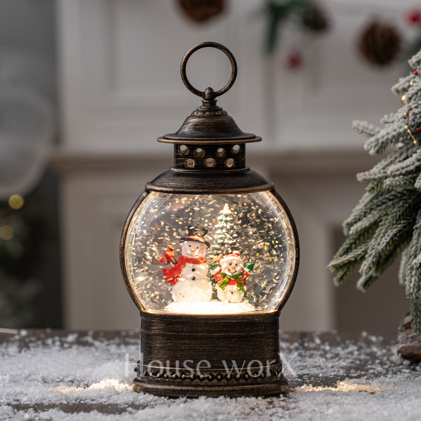 Decorative snow globe with snowmen inside, resembling a lantern, on a snowy surface.