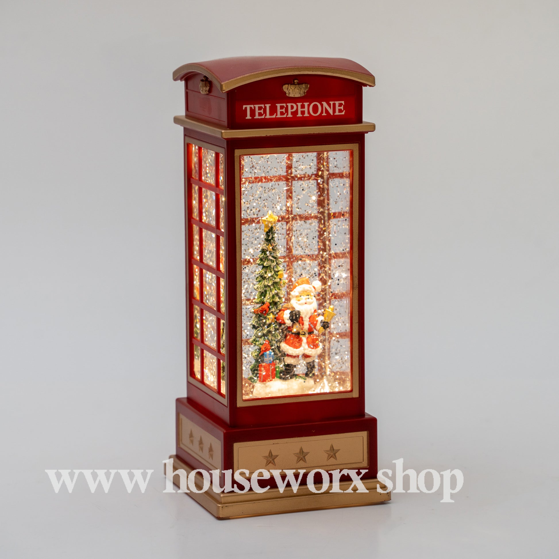 Decorative Christmas scene inside a telephone booth with Santa Claus and a tree, on a gray background. Christmas snow globe
